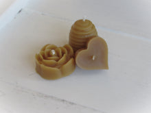 Three beeswax candles shaped like a rose, beehive, and heart.