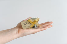 Hand holding a small tea jar with a gold ribbon and personalized label by Lulu Island Honey